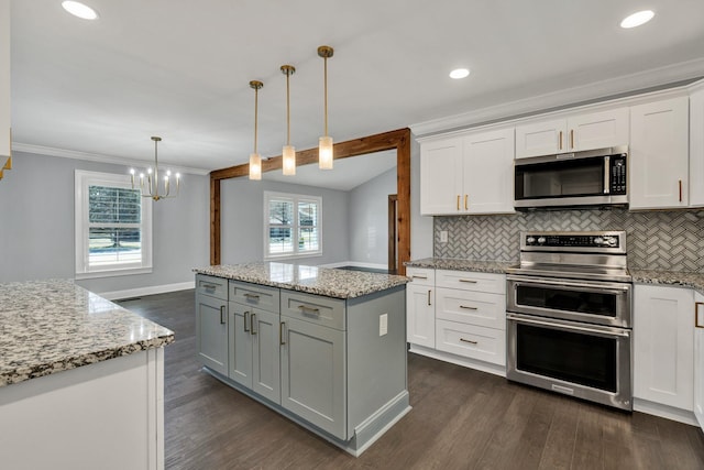 kitchen featuring stainless steel appliances, white cabinetry, a kitchen island, and decorative light fixtures