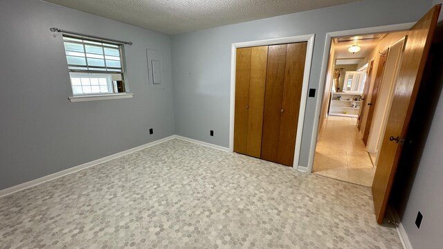 unfurnished bedroom with electric panel, a closet, and a textured ceiling