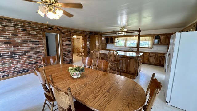 dining area with ceiling fan and brick wall