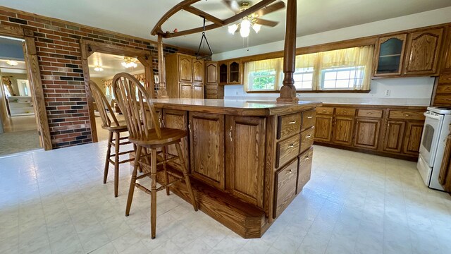 kitchen featuring a breakfast bar, a center island, white range with electric cooktop, and brick wall