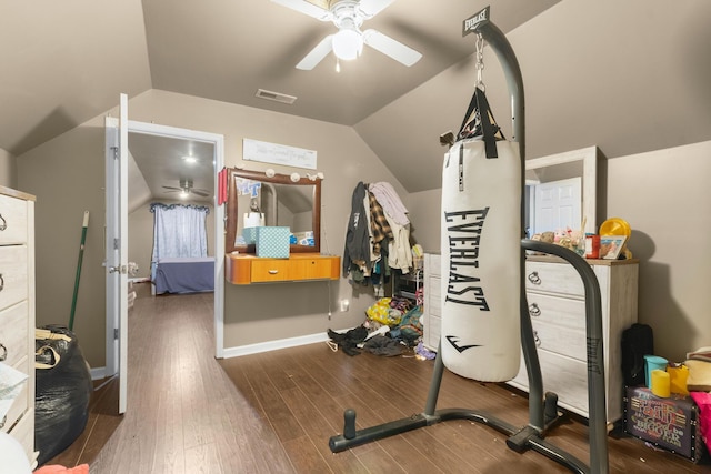 workout room featuring dark wood-type flooring, ceiling fan, and vaulted ceiling