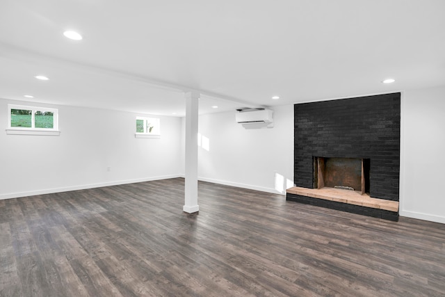 basement featuring dark wood-type flooring, a wall mounted AC, and a brick fireplace