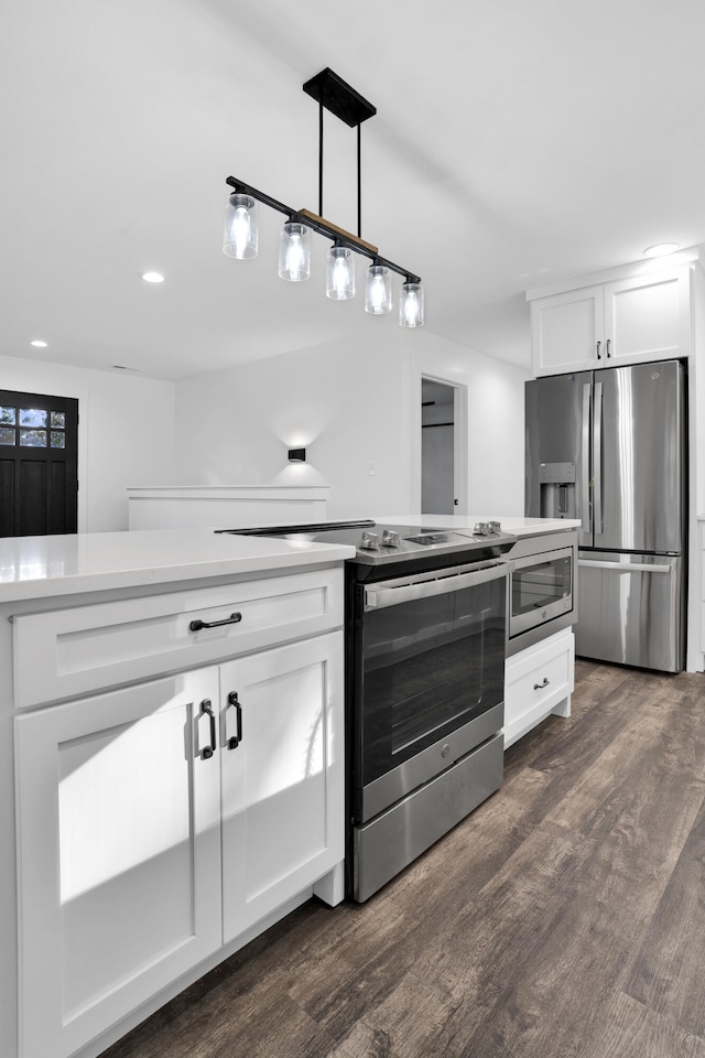 kitchen featuring appliances with stainless steel finishes, dark hardwood / wood-style floors, white cabinetry, and decorative light fixtures