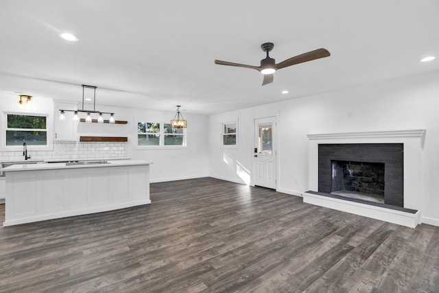 unfurnished living room featuring dark hardwood / wood-style floors, ceiling fan, and a brick fireplace