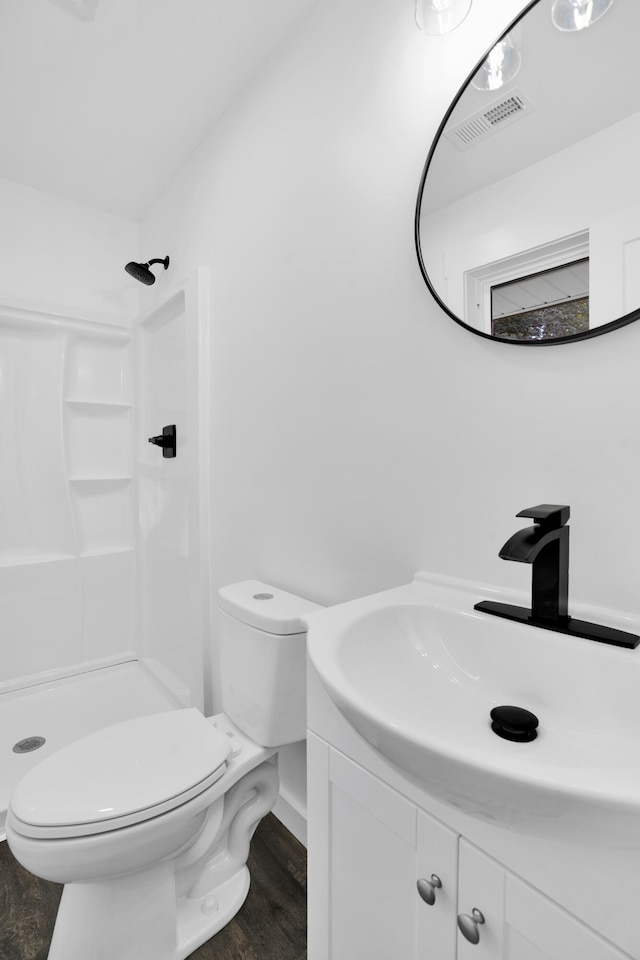 bathroom featuring a shower, toilet, vanity, and hardwood / wood-style flooring