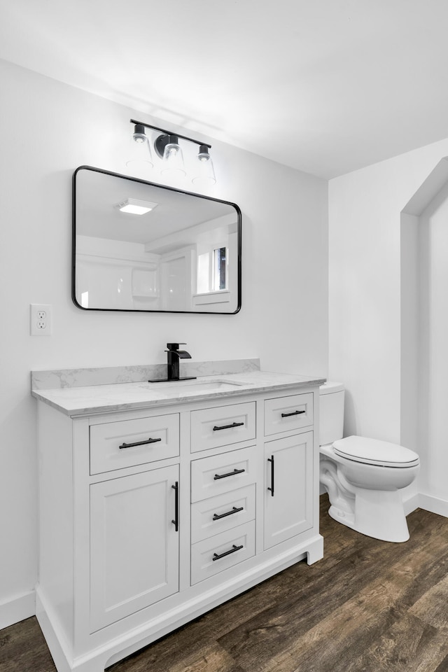 bathroom with toilet, vanity, and hardwood / wood-style flooring