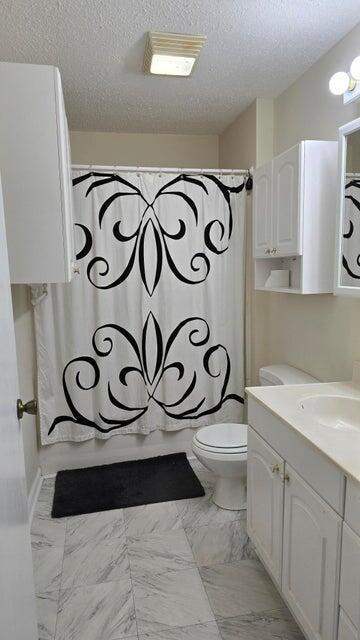 full bathroom with shower / bath combo, vanity, a textured ceiling, and toilet