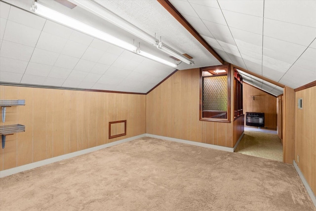 bonus room with heating unit, wood walls, light colored carpet, and vaulted ceiling with beams