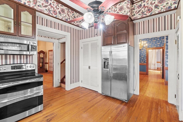 kitchen with ceiling fan with notable chandelier, dark brown cabinets, light wood-type flooring, and stainless steel appliances