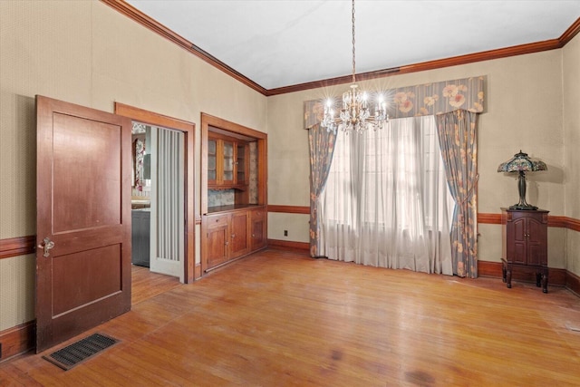 dining room featuring light wood-type flooring, crown molding, and an inviting chandelier