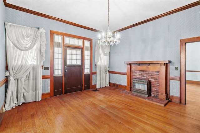 interior space with an inviting chandelier, wood-type flooring, crown molding, and a brick fireplace