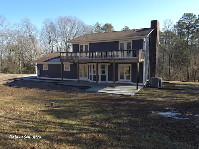 rear view of property featuring french doors, a patio area, central air condition unit, a lawn, and a wooden deck