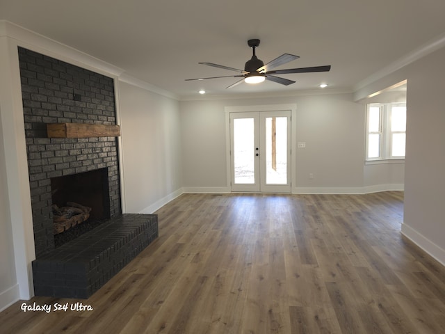 unfurnished living room featuring crown molding, wood-type flooring, a fireplace, and french doors