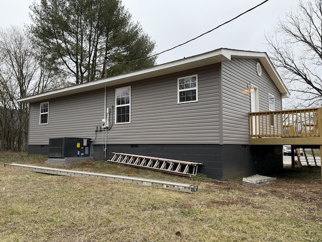 view of side of home with a deck, a lawn, and central air condition unit