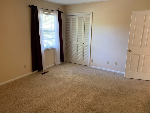 unfurnished bedroom with light carpet and a closet