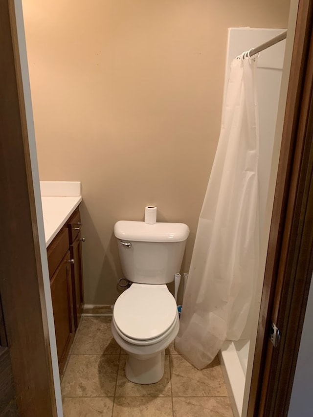 bathroom with a shower with curtain, vanity, toilet, and tile patterned floors