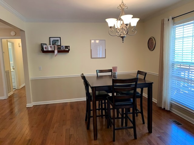 dining space with ornamental molding, dark wood-type flooring, and a notable chandelier