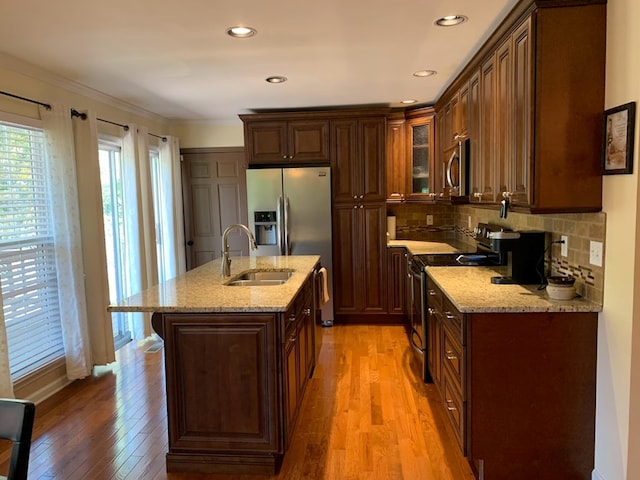 kitchen featuring light stone countertops, stainless steel appliances, light hardwood / wood-style floors, and sink