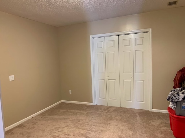 unfurnished bedroom featuring carpet, a textured ceiling, and a closet