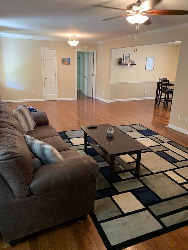 living room with hardwood / wood-style floors, ceiling fan with notable chandelier, and crown molding