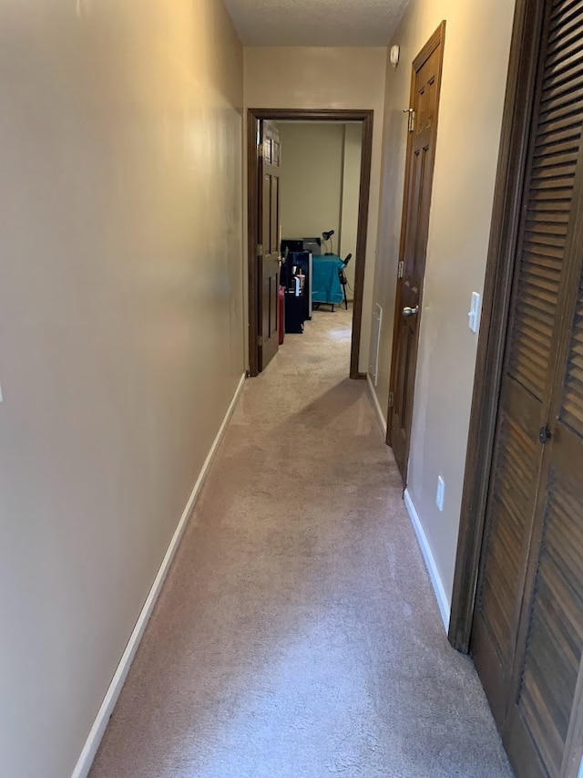 hall with a textured ceiling and light carpet