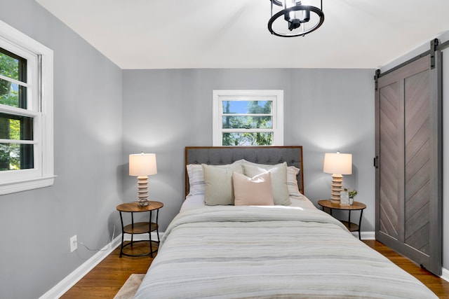 bedroom featuring dark hardwood / wood-style floors and a barn door