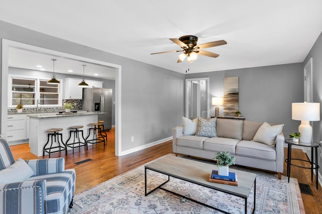 living room featuring ceiling fan, light hardwood / wood-style flooring, and sink