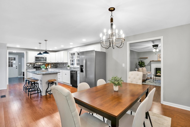 dining room with ceiling fan with notable chandelier and light hardwood / wood-style flooring