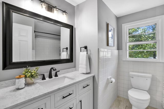 bathroom featuring vanity, toilet, and tile walls