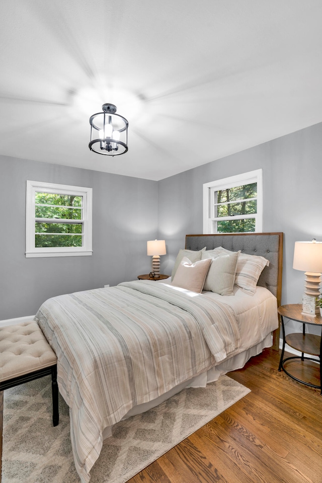 bedroom with hardwood / wood-style floors and a chandelier