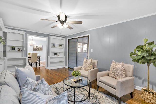 living room featuring hardwood / wood-style floors, wood walls, ceiling fan with notable chandelier, ornamental molding, and built in features