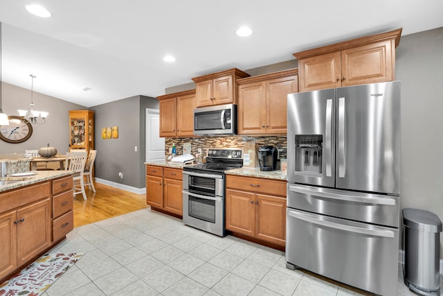 kitchen featuring light stone countertops, an inviting chandelier, tasteful backsplash, vaulted ceiling, and appliances with stainless steel finishes