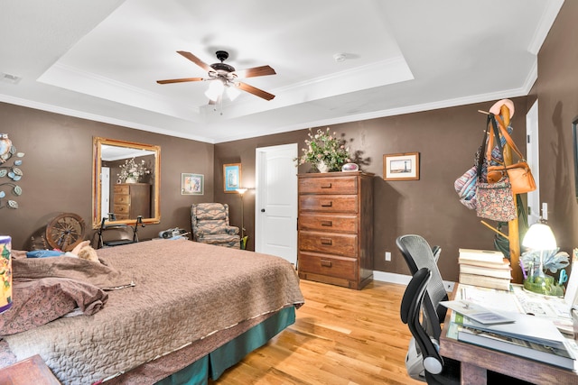 bedroom featuring light wood-type flooring, a tray ceiling, ceiling fan, and crown molding