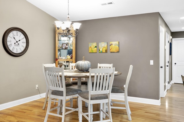 dining space with light hardwood / wood-style floors and an inviting chandelier