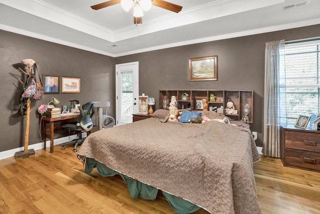 bedroom featuring a tray ceiling, ceiling fan, light hardwood / wood-style floors, and ornamental molding