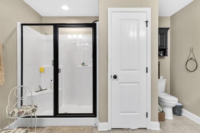 bathroom featuring tile patterned floors, a shower with shower door, and toilet