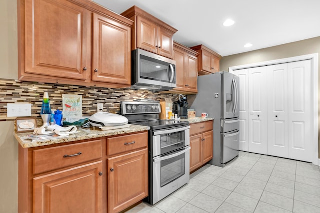 kitchen with decorative backsplash, light tile patterned floors, stainless steel appliances, and light stone counters