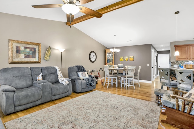 living room featuring vaulted ceiling with beams, ceiling fan with notable chandelier, and light wood-type flooring