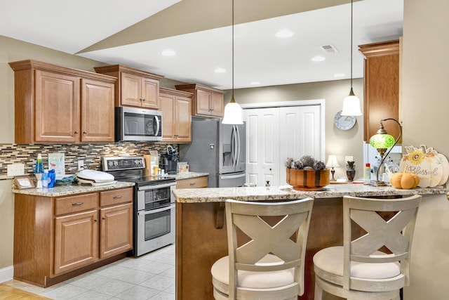 kitchen with a breakfast bar, light stone counters, hanging light fixtures, and stainless steel appliances