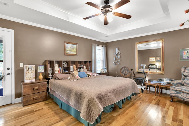 bedroom featuring a raised ceiling, ceiling fan, hardwood / wood-style floors, and crown molding