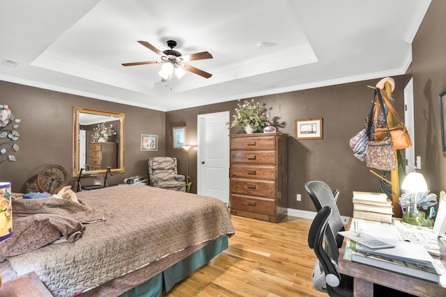 bedroom with light hardwood / wood-style floors, ceiling fan, crown molding, and a tray ceiling