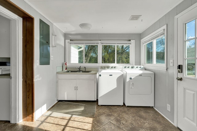 clothes washing area with washing machine and clothes dryer, electric panel, crown molding, and sink