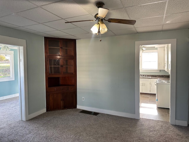 unfurnished room featuring a paneled ceiling, light colored carpet, ceiling fan, and sink