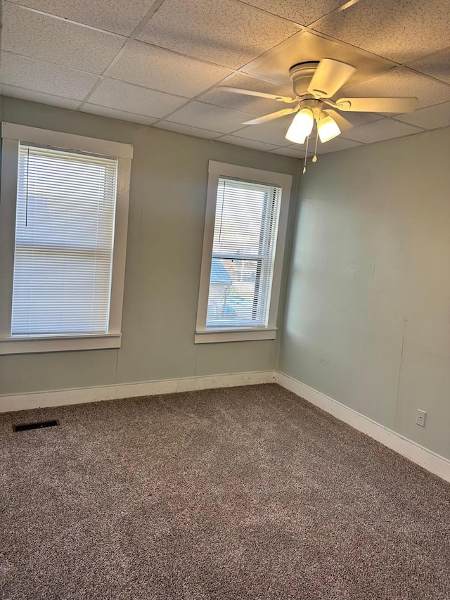 carpeted empty room featuring ceiling fan and a drop ceiling