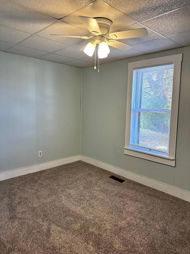 carpeted spare room with a drop ceiling and ceiling fan