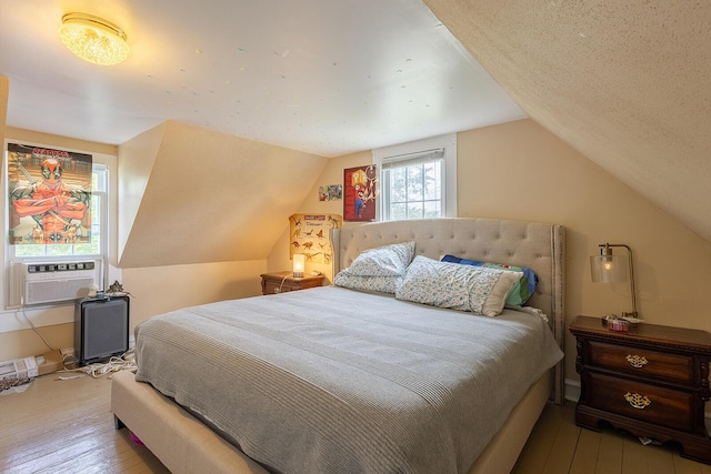 bedroom with hardwood / wood-style flooring, vaulted ceiling, and cooling unit