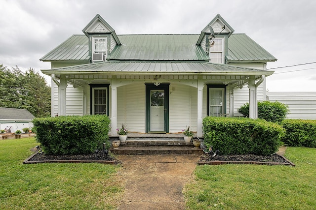 view of front facade with a porch, a front lawn, and metal roof
