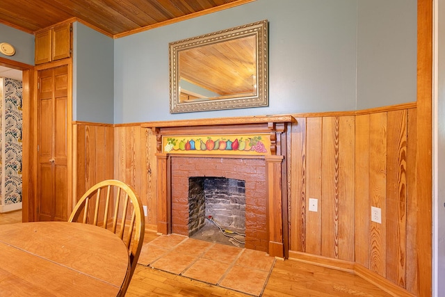 dining room with crown molding, wood walls, a wainscoted wall, wood ceiling, and wood finished floors