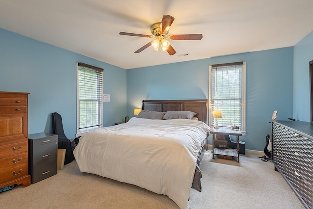 bedroom with multiple windows, light carpet, and a ceiling fan