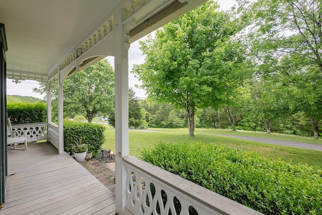 wooden terrace featuring covered porch and a lawn